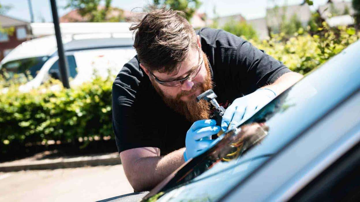 Autoglass technician repairing a windscreen chip